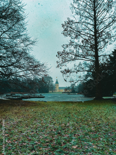 Snowfall Serenity in a Historic European Park with a Baroque Palace Tower Framed by Bare Winter Trees
