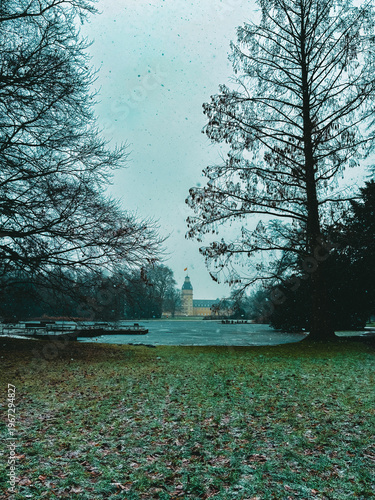 Snowfall Serenity in a Historic European Park with a Baroque Palace Tower Framed by Bare Winter Trees