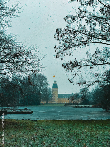 Snowfall Serenity in a Historic European Park with a Baroque Palace Tower Framed by Bare Winter Trees