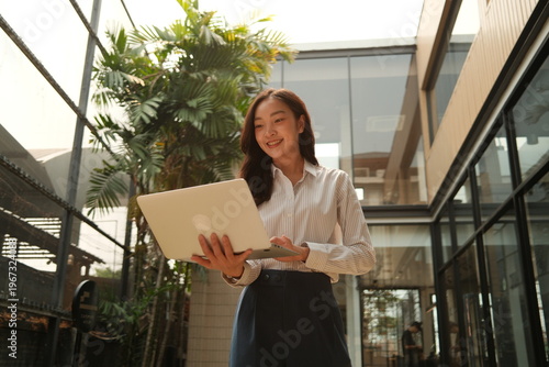 Young businesswoman using laptop outdoor in office courtyard