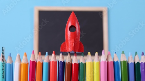 Creative Scene With a Toy Rocket and Colored Pencils on a Desk