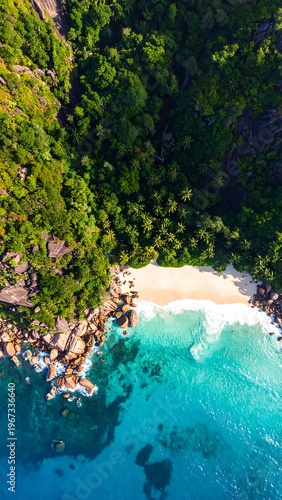 Aerial view of a rocky coastline with lush greenery, sandy beach, and turquoise water