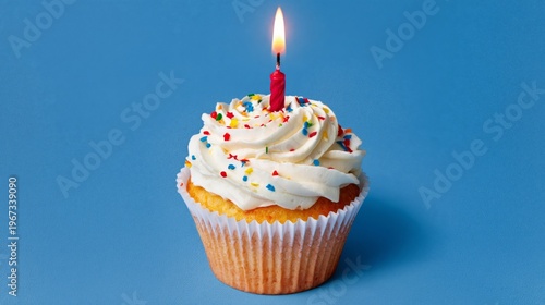 Colorful Birthday Cupcake With a Lit Candle on a Blue Background
