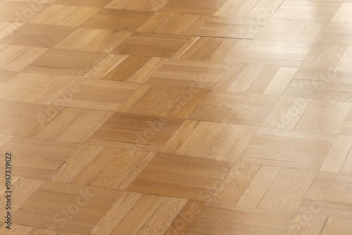 Smooth oak parquet hardwood floor with a warm natural finish and subtle sheen. Geometric square pattern creates a minimalist interior background ideal for design, architecture, product mockups