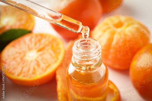 Foto Taking tangerine essential oil from bottle with pipette and fruits on white tabl