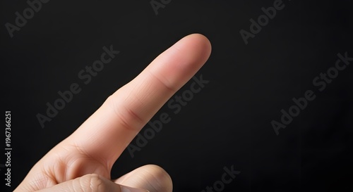 Close-up of a Hand with Extended Index Finger Against Black Background.