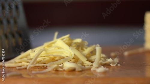 Sprinkling grated cheese onto a wooden chopping board