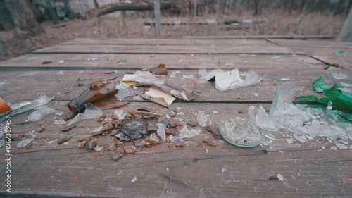 Close-up of Shards of Broken Glass Bottles on Wooden Picnic Table | Danger of Glass Debris and Trash in Nature | Concept of Environmental Pollution and Vandalism