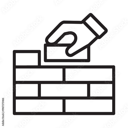 A hand placing a brick onto a partially constructed brick wall