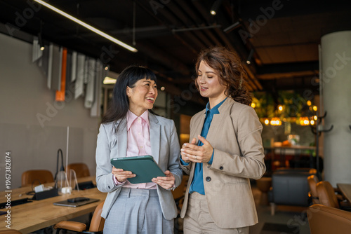 Diverse businesswomen collaborating on digital tablet in modern office