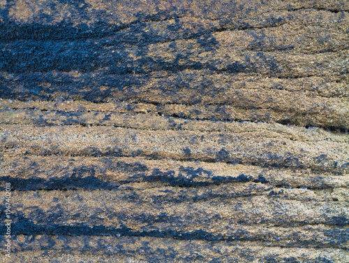 Close up of millstone grit with layered rough texture and cool blue shadows in Yorkshire UK, ideal as a natural stone background.