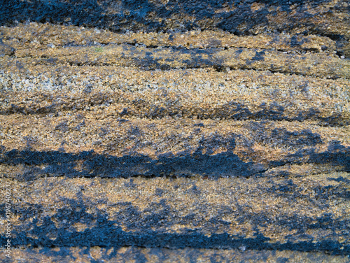 Close up of layered millstone grit in Yorkshire UK with coarse grain and earthy tones creating a rugged natural texture background