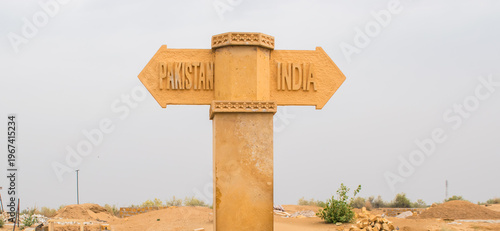 yellow sandstone pillar at the Indo Pak border near Jaisalmer, directional arrows carved on both sides written India on the right, while Pakistan on the left, copy space for text.