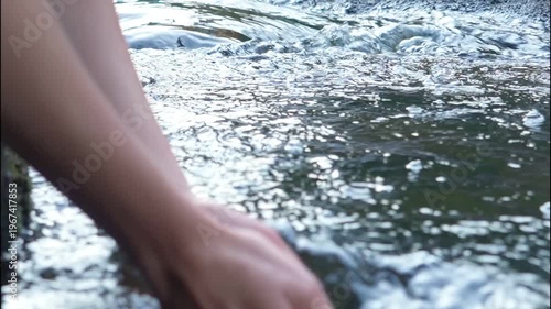 Young woman drinking fresh water from a clean forest stream in summer. Pure nature, peace, and refreshment. A quiet moment in the wilderness, symbol of connection with nature and natural living.
