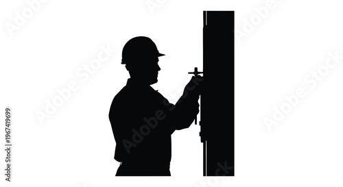 Construction worker adjusts a tool against a wall stark silhouette