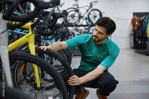 Skilled male technician thoroughly inspects bicycle wheel quality