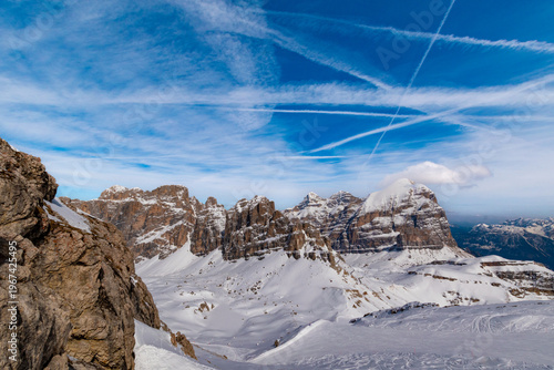 Snow covered Dolomites peaks near Lagazuoi in winter with dramatic clouds and contrails Italy