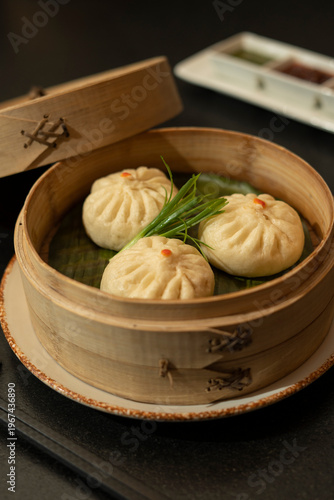 Steamed dumplings in bamboo steamer basket served on plate with garnish