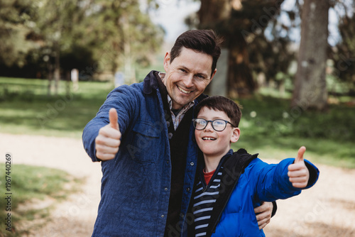 Father and son showing thumbs up smiling together outdoors