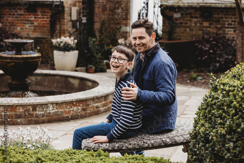 Father and son sitting together outdoors laughing in garden