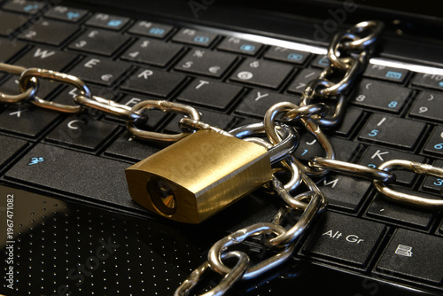 Computer security concept with an iron chain and padlock on the laptop keyboard