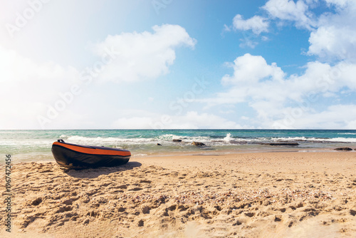 A rubber inflatable boat is docked on a sandy beach