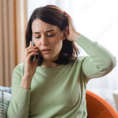 Frustrated Asian Woman on Smartphone in Home Office During Stressful Remote Work Call