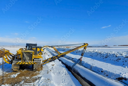 Laying pipelines in ditch with the help of pipelayer loaders, construction of oil pipelines and gas pipelines in remote areas.