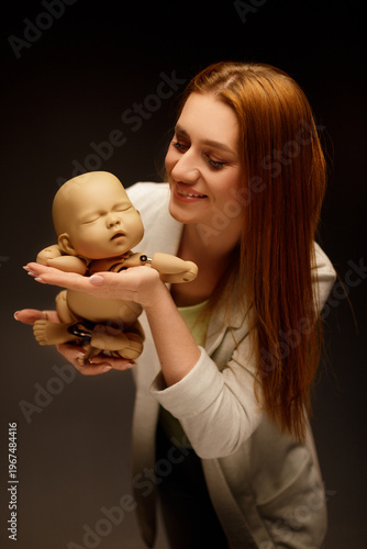 Young woman smiling while holding a baby mannequin