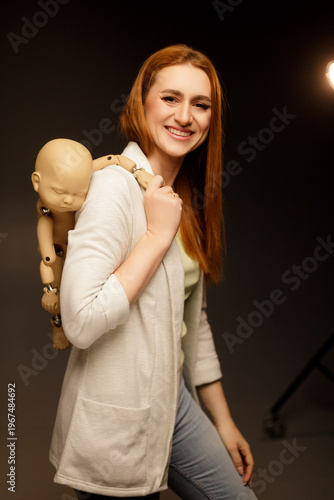 Smiling woman carrying a baby mannequin on her back