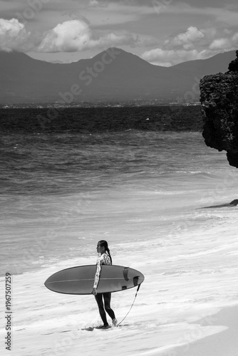 A beautiful girl surfs in a jumpsuit in the middle of the ocean waves