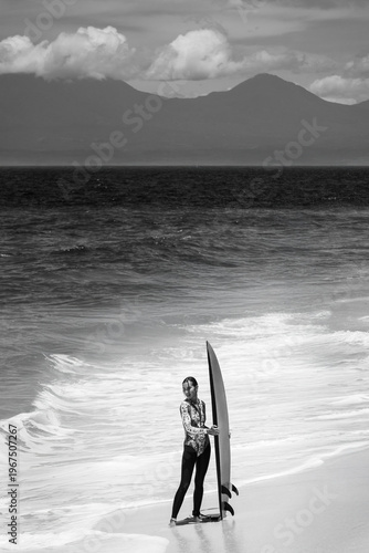 A beautiful girl surfs in a jumpsuit in the middle of the ocean waves