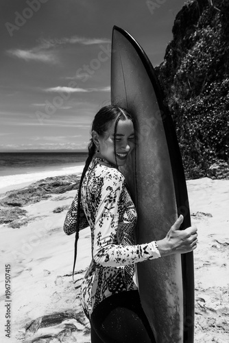 A beautiful girl surfs in a jumpsuit in the middle of the ocean waves
