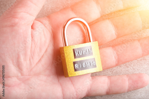 Golden padlock with Human Rights text placed on an open palm, symbolizing protection and security civil liberties.