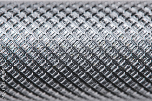 Extreme macro texture metal tool handle with knurled diamond pattern, showing industrial detail and steel surface.