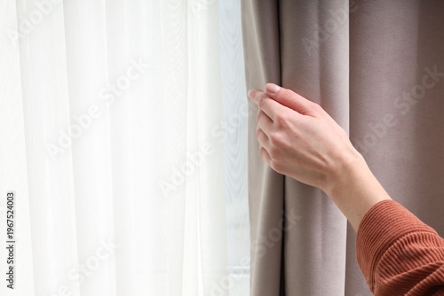 Φωτογραφία Woman opening stylish window curtains at home, closeup