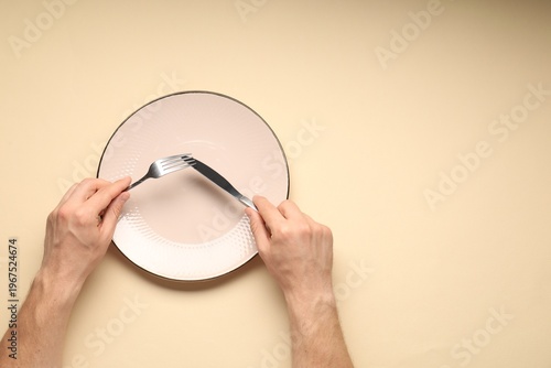 Bild auf Leinwand Man with cutlery and plate on beige background, top view