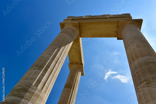 Lindos Acropolis, Lindos, Rhodes Island, Greece. The tall column and cornice of an archeological Roman-Greek temple site of Athena from the 4th century BC in Spring.