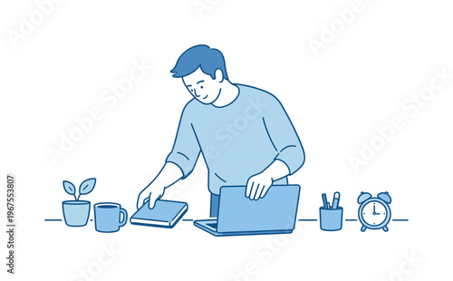 Man organizing workspace desk during calm morning routine, standing at desk arranging notebook and laptop with focused relaxed