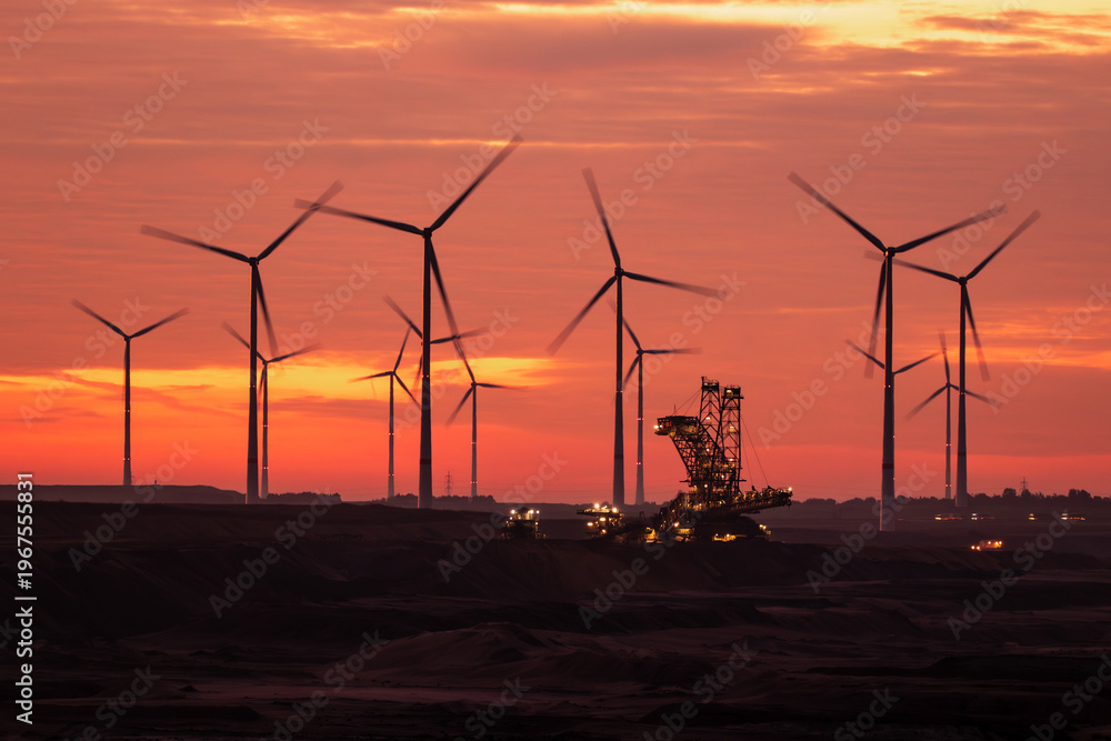 Obraz premium Open-pit coal mine excavator and windfarm during sunrise at Garzweiler, Germany