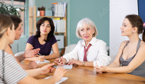 Fotografie Positive group of women sitting at a table and actively discussing solutions dur