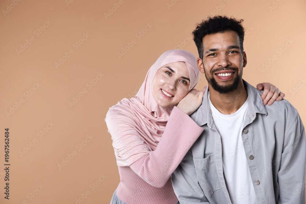 Fototapeta premium Portrait of happy muslim couple on beige background. Space for text
