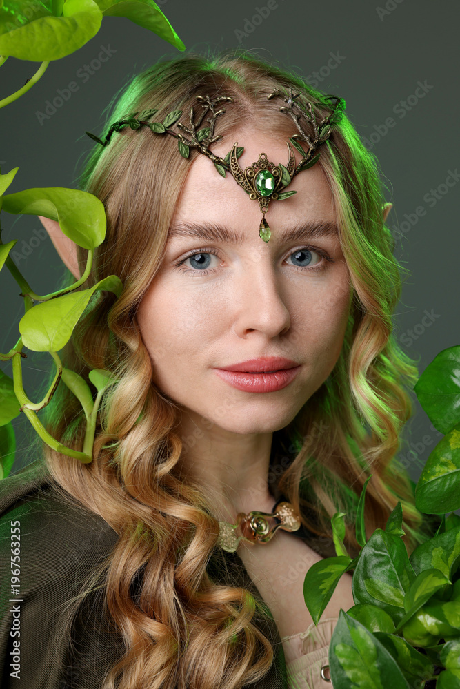 Obraz premium Beautiful elf girl and green leaves on grey background