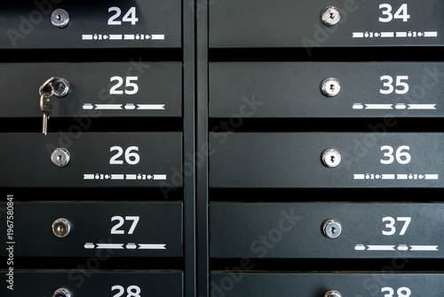 Black metal mailbox units with numbered slots and key in lock