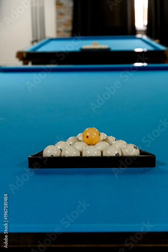 Pool table with triangle rack of billiard balls on blue felt surface