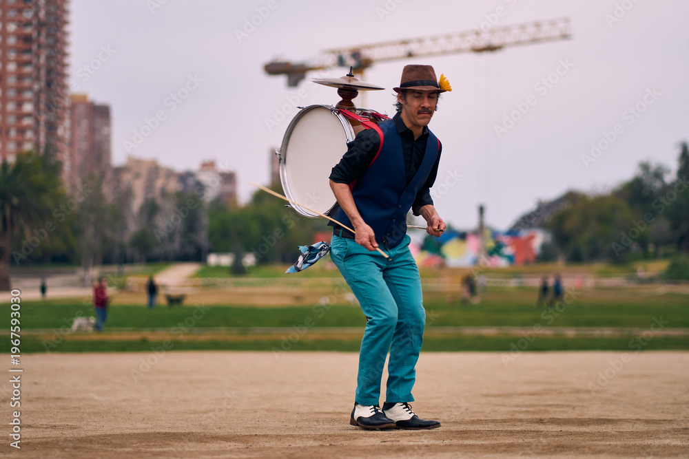Obraz premium Latin American man posing with a bass drum on his back, dancing and spinning, Chilean chinchinero, street musician who plays the bass drum and cymbals and dances in the streets, Chilean cultural.