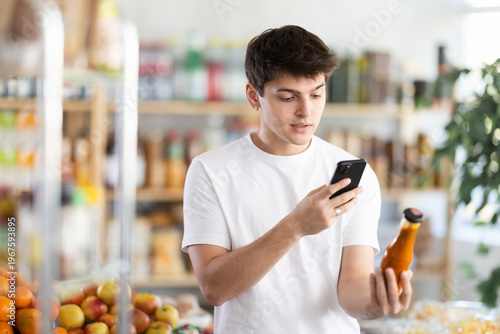 Obraz na plátne Guy customer at shop scan QR code on sauce bottle using phone camera