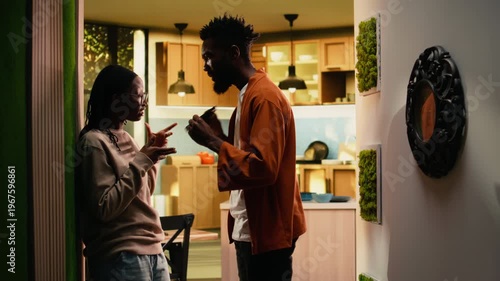 Jealous offended man controlling smartphone and worrying about dishonesty or infidelity, obsessive boyfriend starting a fight with girlfriend. Toxic relationship with suspicion and distrust.