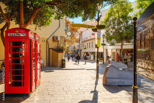 Fotografie The entrance into Main Street, the central shopping and dining street through the historic old town, with an iconic red K6 kiosk telephone box in Gibraltar, a British Territory on the south of Spain