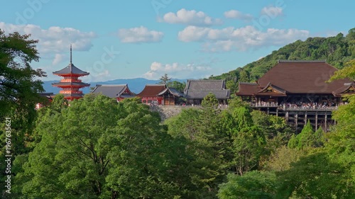 Kyoto, Japan - Oct 11 2024, 4k, panoramic view through foliage of Kiyomizu-Dera temple complex with a pagoda, without people, with a clear blue sky and a forest in foreground, at daytime, Kyoto, Japan